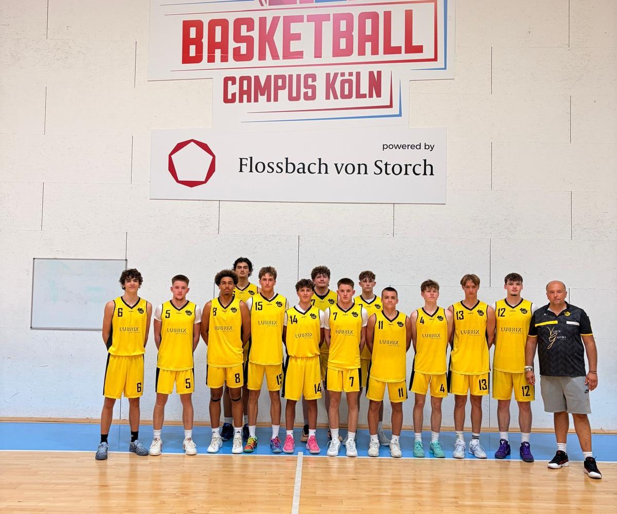 Teamfoto der Kirchheimer U18 in gelben Trikots mit Trainer Miloš Jovanović in der Halle in Köln